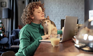 Vrouw kijkt op  beeldscherm laptop kat op toetsenbord