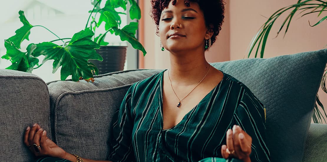 Vrouw die thuis op de bank een mindfulness oefening doet