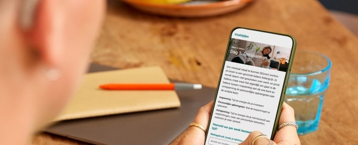 Hier zie je iemand die een online vitalitijdje volgt op de smartphone